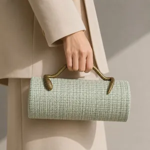 Close-up detail of a woven cylindrical evening clutch with a metallic snake-shaped handle