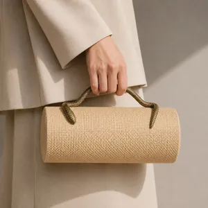 Close-up detail of a chic cylindrical evening clutch with a golden snake handle.
