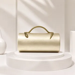 Close-up of a champagne gold cylindrical evening bag with a unique snake-shaped handle