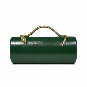 Detailed view of dark green cylindrical evening bag with gold snake handle.