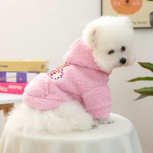 Dettaglio felpa in pile rosa per animali con ricamo a margherita su cane bianco.