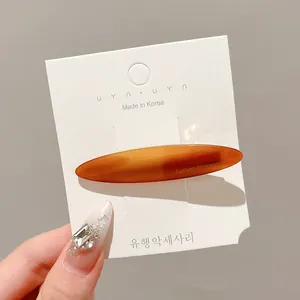 Elegant amber oval duckbill hair clip presented on a minimalist Korean style display card