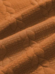 Detailed macro shot of textured jacquard fabric in burnt orange for men's sweatshirt