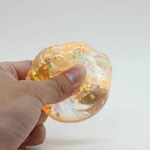 Nahaufnahme einer Hand, die ein orangefarbenes Glitzer-Katzenpfoten-Squishy-Spielzeug drückt