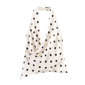 Detail view of a white polka dot halter top with silky satin texture and draped front