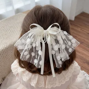 Detailed close-up of a sweet lace bow hair clip with pearls and floral appliques for little girls