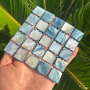 Detailed view of iridescent natural shell mosaic coaster with square blue tiles