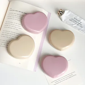 Detailed view of glossy heart-shaped contact lens cases in pink and beige candy colors
