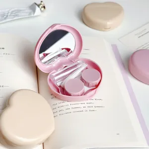 Detailed view of heart-shaped contact lens case with mirror and tools in pink.