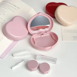 Close-up of pink heart-shaped contact lens case kit with tweezers and mirror