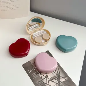 Detail of open heart contact lens case with mirror, tweezers, and mini bottle.