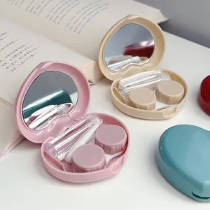 Close-up of heart-shaped contact lens cases in pink and beige with built-in mirrors