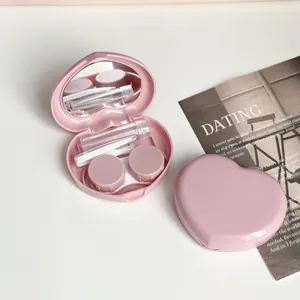 Detailed macro view of a pink heart-shaped contact lens travel case with mirror and tools