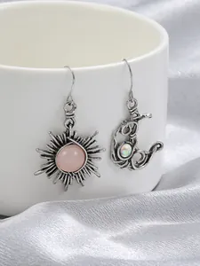 Macro view of vintage distressed sun and moon drop earrings with pink gemstones