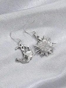 Detailed shot of retro silver sun and moon mismatched drop earrings with textured finish