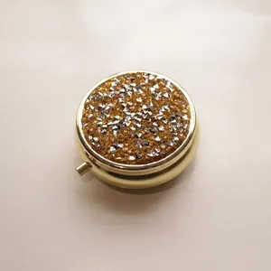 Macro detail view of a circular gold metal pill box with sparkling rhinestone inlay