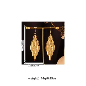 Close-up detail of oversized gold metal leaf tassel earrings with size and weight