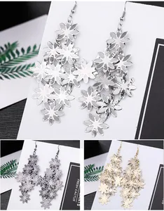 Macro detail of long floral tassel drop earrings in silver, gold, and black colors.