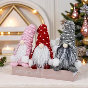 Vue détaillée de trois gnomes de Noël tricotés posés sur un socle de décoration.