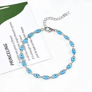 Gros plan d'un bracelet œil de protection argenté avec perles bleues sur décor blanc.