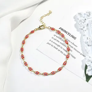 Vue détaillée d'un bracelet en chaîne dorée orné de perles rouges de l'œil maléfique