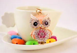Close-up of a cute rhinestone-encrusted owl keychain hanging on a white ceramic cup