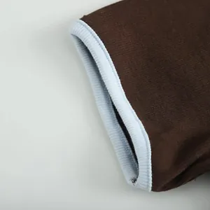 Detailed macro shot showing the light blue ribbed cuff on a dark brown cotton knit t-shirt