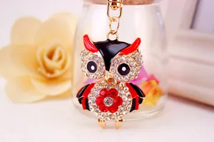 Macro view of a cute cartoon owl keychain with sparkling rhinestones and red enamel.