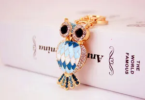 Close-up of a glittering gold-plated owl keychain with blue enamel and rhinestones