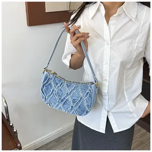 Close-up of a stylish light blue denim crescent shoulder bag with distressed texture