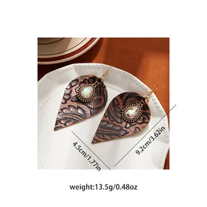 Detailed macro view of retro embossed leather leaf earrings with sparkling rhinestones