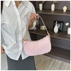 Model holding a pink denim crescent shoulder bag with textured fringe diamond pattern