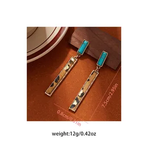 Detailed view of vintage leopard print drop earrings with turquoise stone accents.