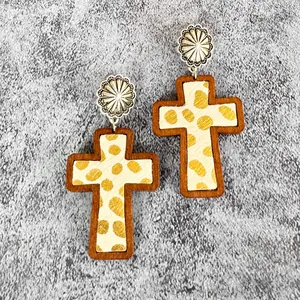 Detail shot of cross earrings with leopard print fur, wood frame, and flower stud.