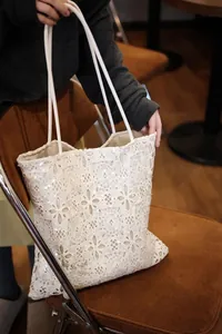 Detailed view of a white French-style lace tote bag with elegant sequin floral patterns.