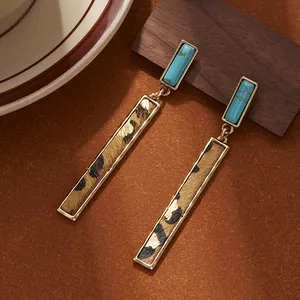 Detailed view of retro leopard print leather bar earrings with turquoise stone accent