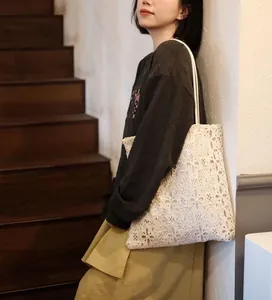 Detail of white French lace shoulder bag with sequins on Asian model in lifestyle setting.