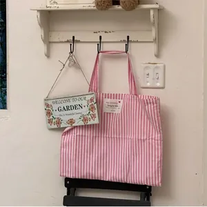 Close-up of a pink and white striped canvas tote bag hanging on a hook in a home setting