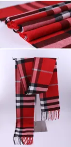 Close-up view of a soft red and black plaid winter scarf featuring stylish fringed edges