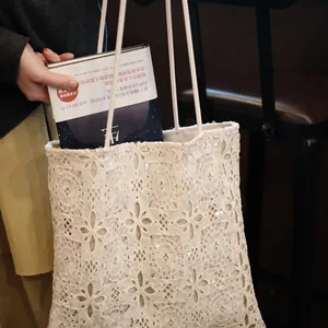 Close-up detail of a white lace sequin embroidered tote bag being used with a book.