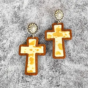 Detailed macro view of Western style wooden cross earrings with cow print leather inlay