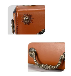 Close-up of vintage sun face emblem and ornate metal handle on brown leather handbag