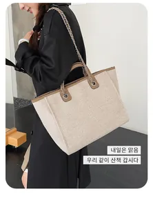 Large beige textured tote bag with elegant chain strap and brown trim worn by model
