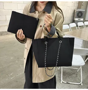 Stylish black canvas tote bag with silver chain strap and matching inner clutch