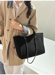Stylish large capacity black tote bag with elegant silver chain strap carried by a model