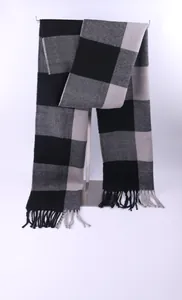 Detailed macro view of a black and grey buffalo check winter scarf with tassels.