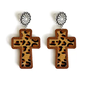 Close-up detail of leopard print leather and wood frame on Western cross earrings.