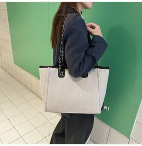 Stylish large capacity canvas tote bag with chain strap carried by model in professional attire