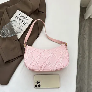 Stylish pink denim crescent shoulder bag featuring a unique fringed diamond pattern design.