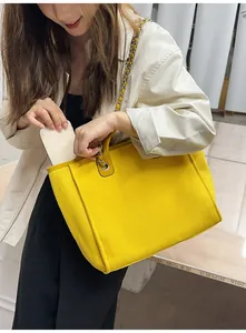 Detail view of a stylish large capacity yellow canvas tote bag featuring a metal chain strap